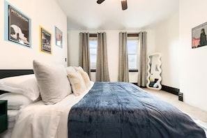 A bedroom with a bed, curtains, and wall art. - Designer Rowhouse w/ Themed Bedrooms, Fireplace & Arcade — Perfect for Groups (Pittsburgh)