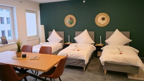 Quarto de hotel com duas camas de solteiro, uma mesa de madeira com cadeiras e vista para o exterior.