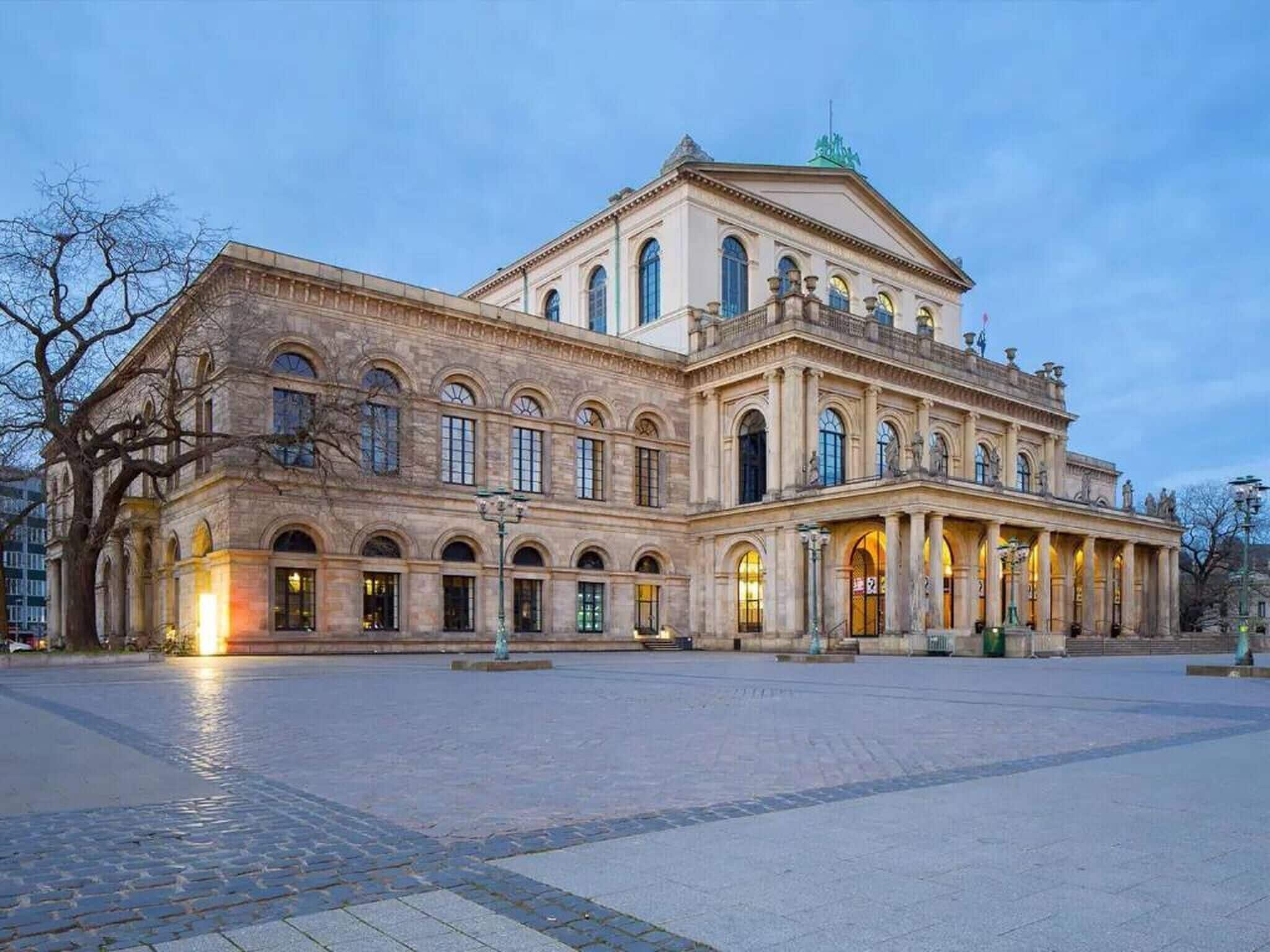 Un edificio grande e histórico con fachada simétrica, ventanas en arco y una entrada central.