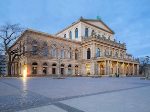 Un edificio grande e histórico con fachada simétrica, ventanas en arco y una entrada central.