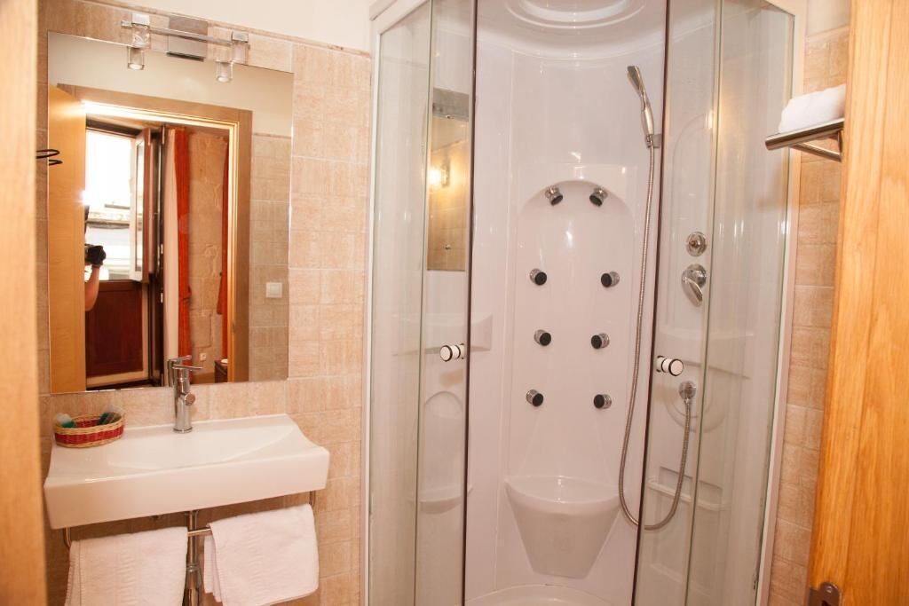 A modern bathroom with a glass-enclosed shower, a white sink, and a mirror.