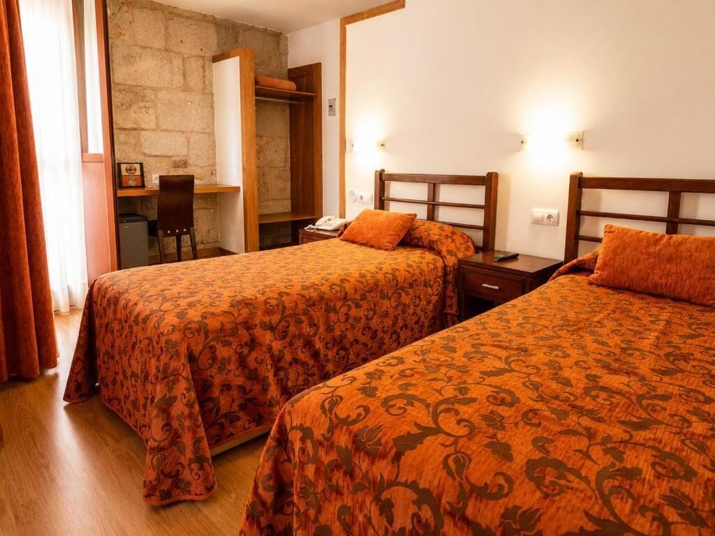 A hotel room with two beds, a desk, and a wardrobe.