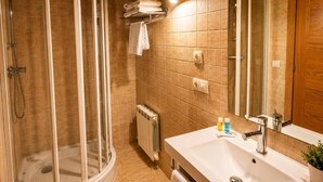 A bathroom with a shower enclosure, a sink, a mirror, and a towel rack.