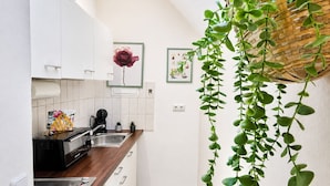 Een moderne keuken met witte kastjes, een houten aanrecht, een koffieapparaat en een hangplant.