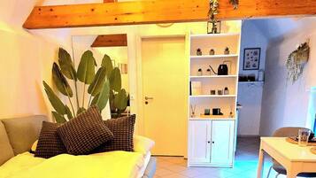 A cozy room with a bed, a small table, and a kitchen area.