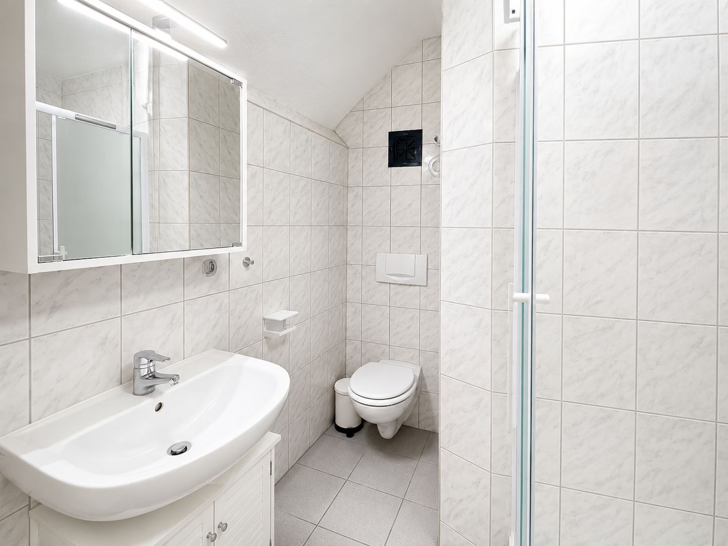 Een badkamer met een witte wastafel, spiegel en toilet.