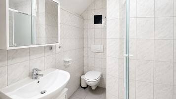 A bathroom with a white sink, mirror, and toilet.