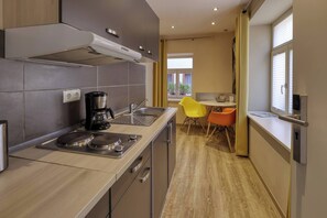 Una cocina moderna con cafetera, lavamanos y zona de comedor con mesa y sillas.