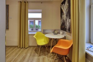 Una habitación con ventana, una mesa, dos sillas y un cuadro en la pared.