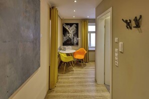 Un pasillo con una zona de comedor que incluye una mesa y sillas, un cuadro en la pared y una puerta con interruptor de luz.