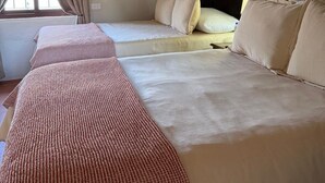 Quarto com duas camas, teto de madeira e janela com cortinas.