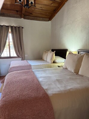 A room with two beds, a wooden ceiling, and a window with curtains. - La Ermita de Santa Lucia (Antigua)