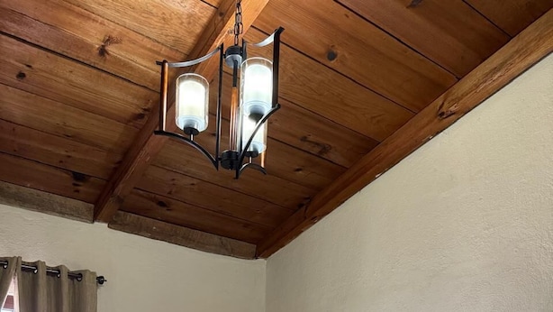 Quarto de hotel com duas camas, teto de madeira, janela com cortinas e mesa de cabeceira com abajur.