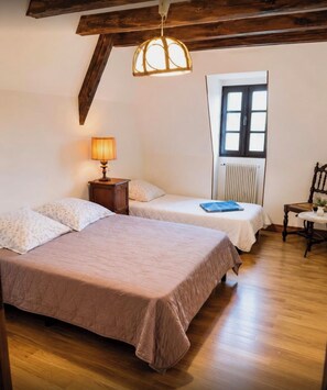 Een kamer met twee bedden, een raam, een radiator, een lamp en een stoel.