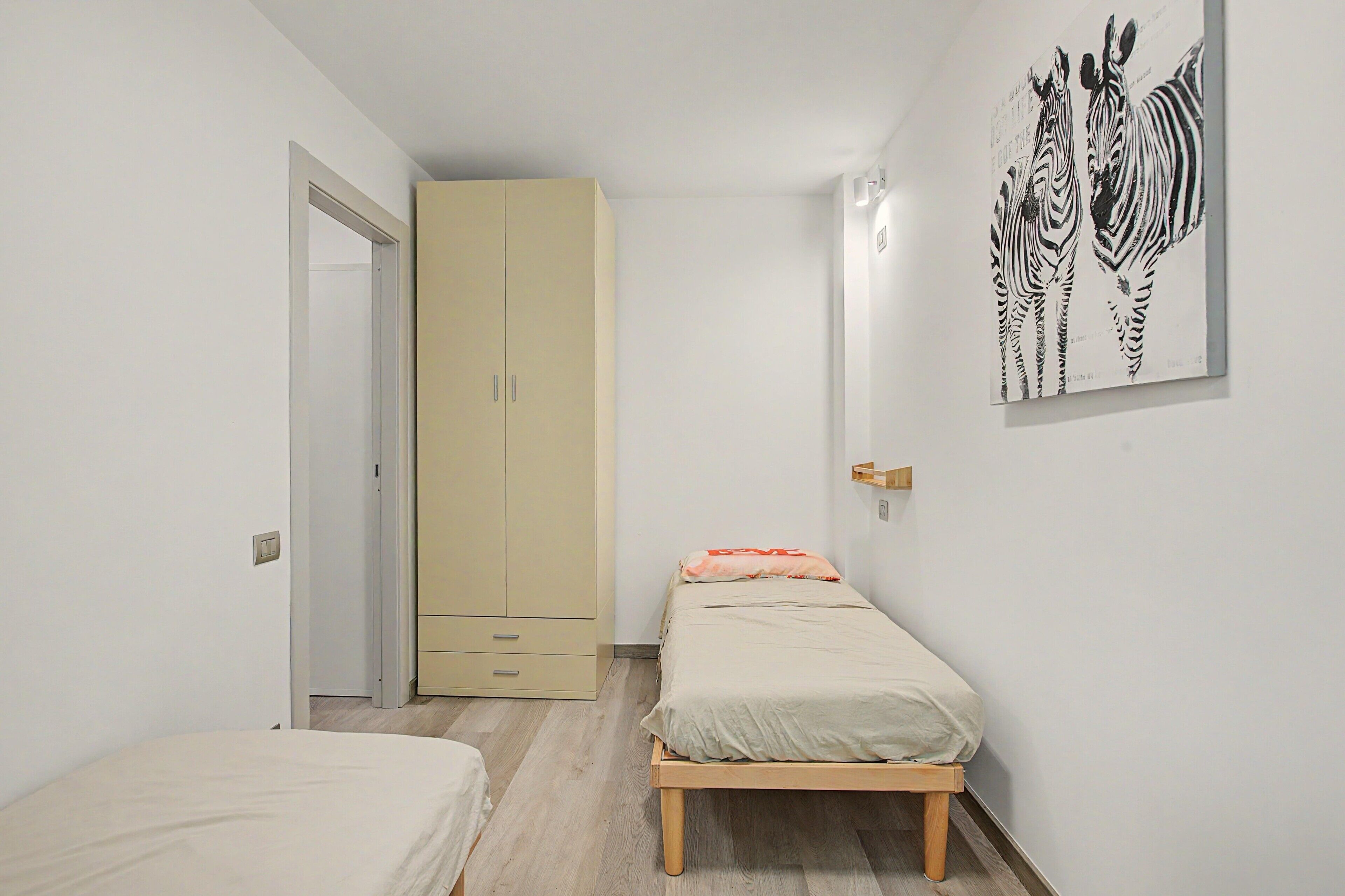 Ein Schlafzimmer mit einem Bett, einem Kleiderschrank, einer Wandleuchte und einem Zebra-Motiv.