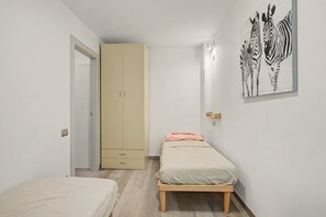 Une chambre à coucher comprenant un lit, une armoire, une lampe fixée au mur et une œuvre d’art représentant un zèbre.