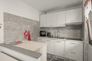 Une cuisine moderne avec des armoires blanches, un évier en acier inoxydable et un four à micro-ondes.