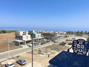 Un quartier résidentiel situé sur la côte, avec des immeubles modernes, une route et des voitures garées.