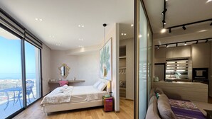 Een moderne slaapkamer met een groot bed, een bank, een eethoek en uitzicht op de stad.