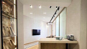 Een moderne hotelkamer met een houten vloer, een flatscreen televisie aan de muur, een houten aanrecht en een grote spiegel.