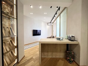 Une chambre d’hôtel moderne avec un plancher en bois, un téléviseur à écran plat fixé au mur, un comptoir en bois et un grand miroir.
