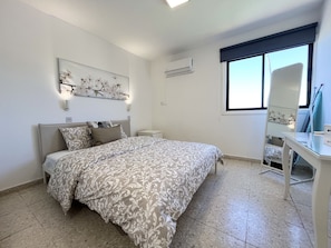 Ein Schlafzimmer mit Bett, Nachttisch, Wand-Klimaanlage und Fenster mit Blick.