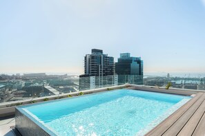 A rooftop infinity pool with a city view, surrounded by a wooden deck. - Skyline Retreat | Heart of Cape Town (Cape Town)