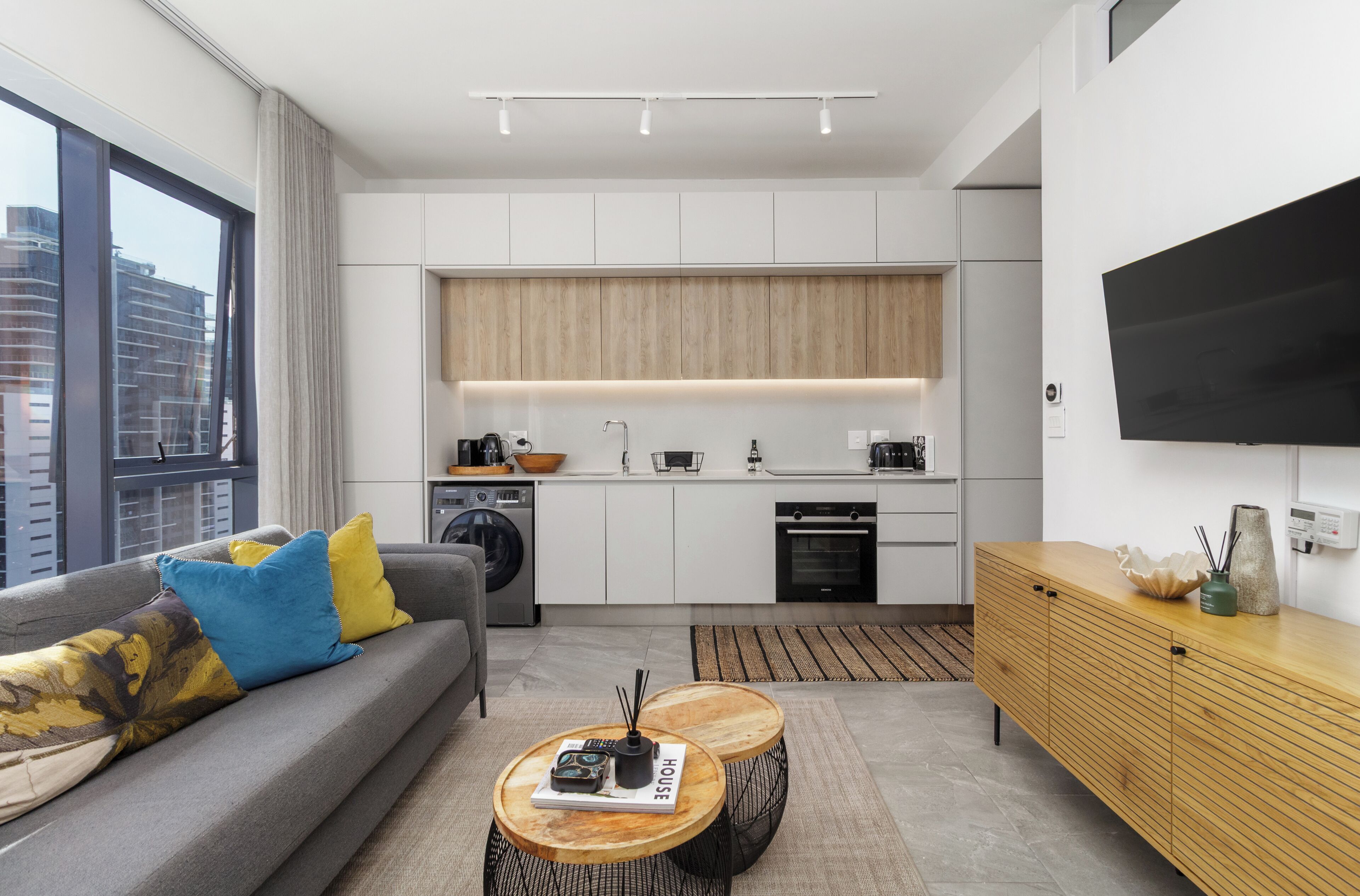 Un apartamento moderno con zona de estar, kitchenette y un amplio ventanal.