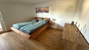 A bedroom with a wooden bed, a nightstand, a wall-mounted lamp, and a painting.