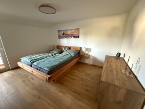 Makuuhuoneessa on puinen sänky, yöpöytä, seinään kiinnitetty lamppu ja taulu.