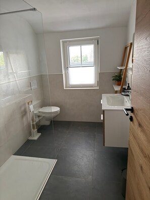 Kylpyhuoneessa on wc, pesuallas ja suihku. WC:n yläpuolella on ikkuna.