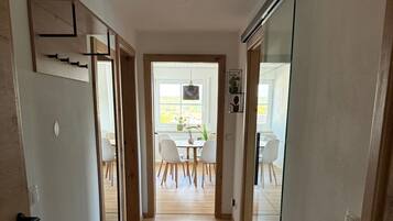 Un pasillo con suelo de madera que lleva a un comedor con una mesa y sillas.
