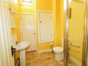 A bathroom with a sink, toilet, and shower area. - The Mummers Studio Apartment 1 (Enniskillen)