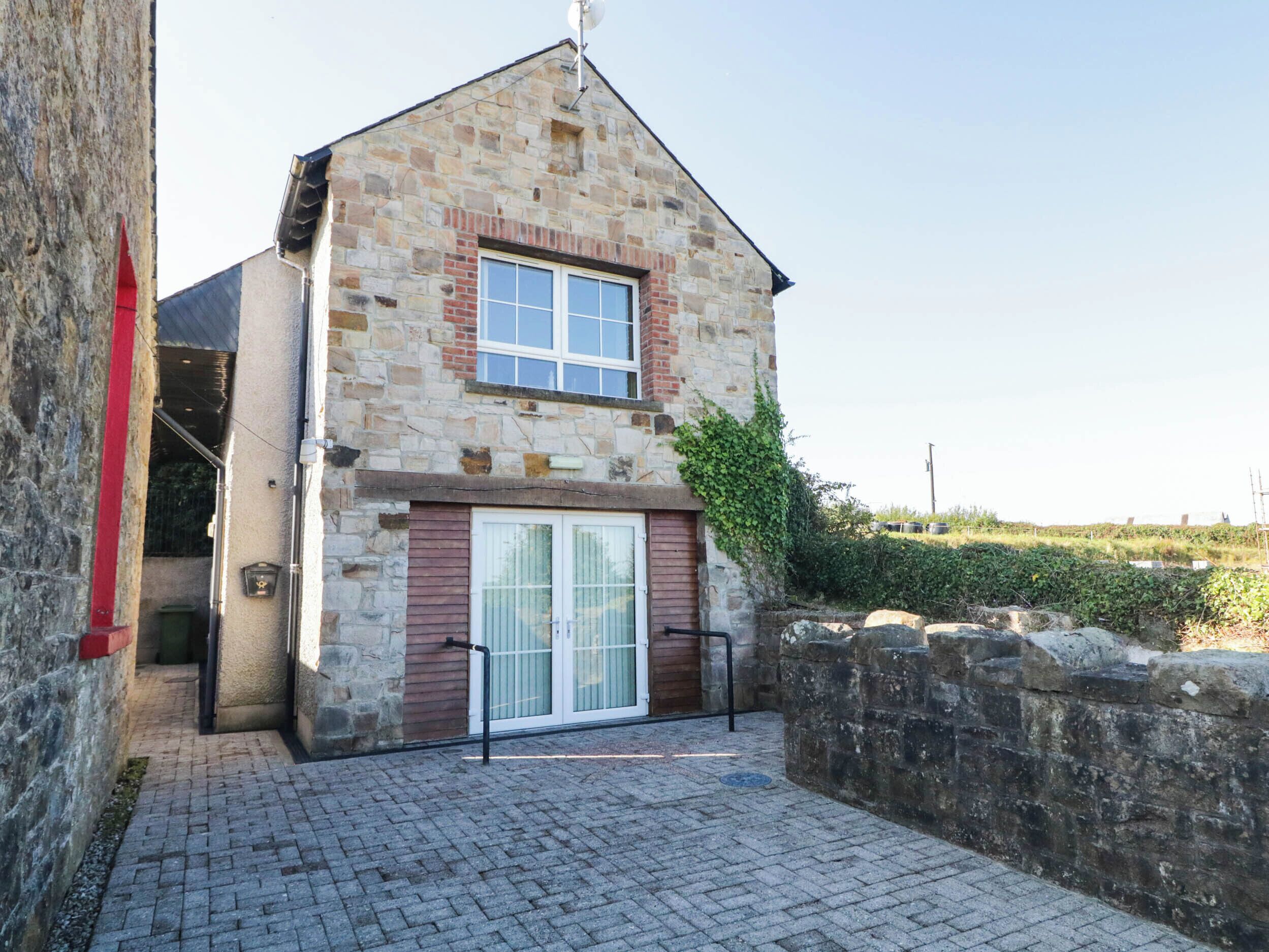 A stone building with a tiled entrance and a small garden area.