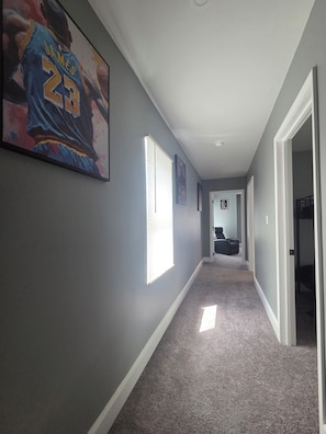 A hallway with a carpeted floor, a basketball player poster, and a door leading to another room. - Terrific 3-bedroom house with AC , one and a half bath in charming Zanesville oh (Zanesville)