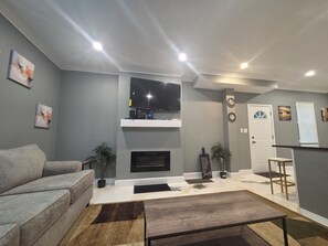 A modern living room with a grey sofa, a flat-screen TV, a fireplace, and a small table. - Terrific 3-bedroom house with AC , one and a half bath in charming Zanesville oh (Zanesville)