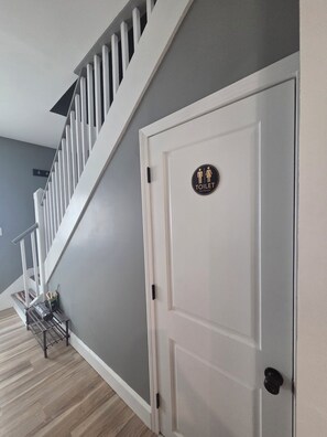 Un escalier avec des rampes blanches menant à une porte sur laquelle est apposé un panneau indiquant les toilettes.