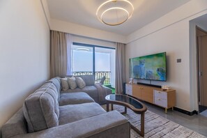 A modern living room with a sectional sofa, a flat-screen TV, and a glass coffee table. - The Safari view Gateway | 10 Min JKIA | 5 Min SGR (Nairobi)