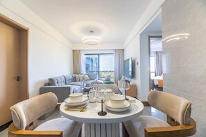 A modern hotel room with a dining table set for two, a sofa, a TV, and a balcony view. - The Safari view Gateway | 10 Min JKIA | 5 Min SGR (Nairobi)