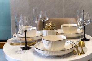A table set with white plates, bowls, and gold cutlery, accompanied by wine glasses. - The Safari view Gateway | 10 Min JKIA | 5 Min SGR (Nairobi)