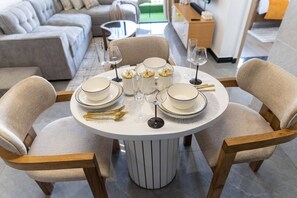 A round dining table with four chairs, set with white plates, gold cutlery, and clear wine glasses. - The Safari view Gateway | 10 Min JKIA | 5 Min SGR (Nairobi)