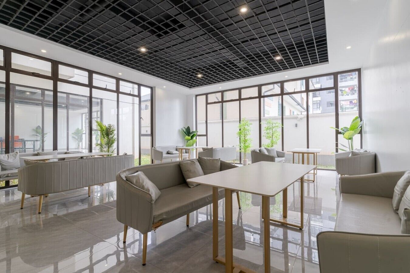 Un espace de bureau moderne doté d’une grande fenêtre, d’un canapé, d’une table et d’une plante.