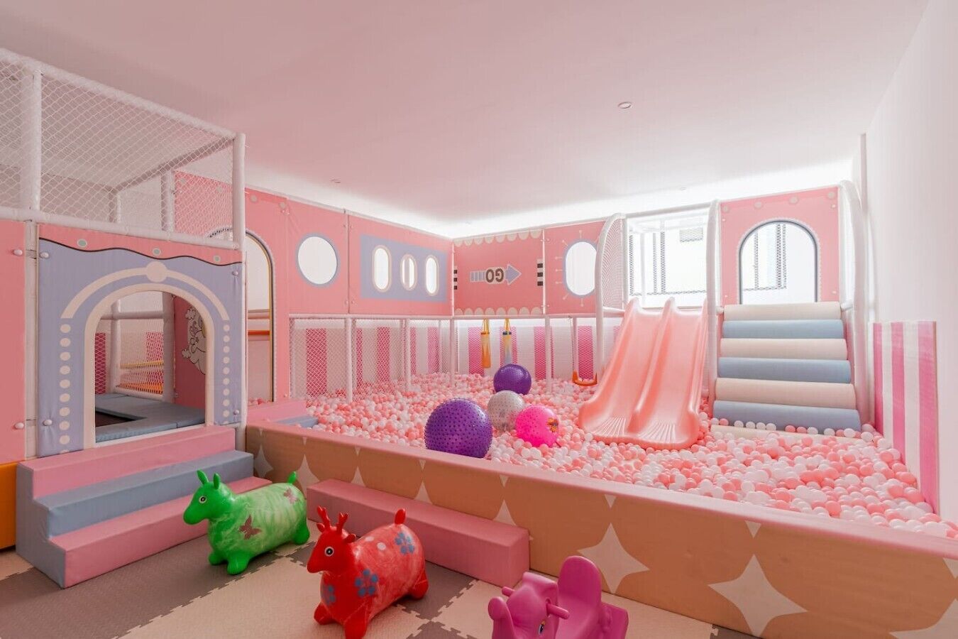 Een kinderspeelruimte met een bällebad, glijbanen en zachte speeltoestellen.