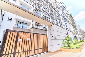 A multi-story residential building with a gated entrance, balconies, and a landscaped garden area. - Azure Luxe Residence (Nairobi)