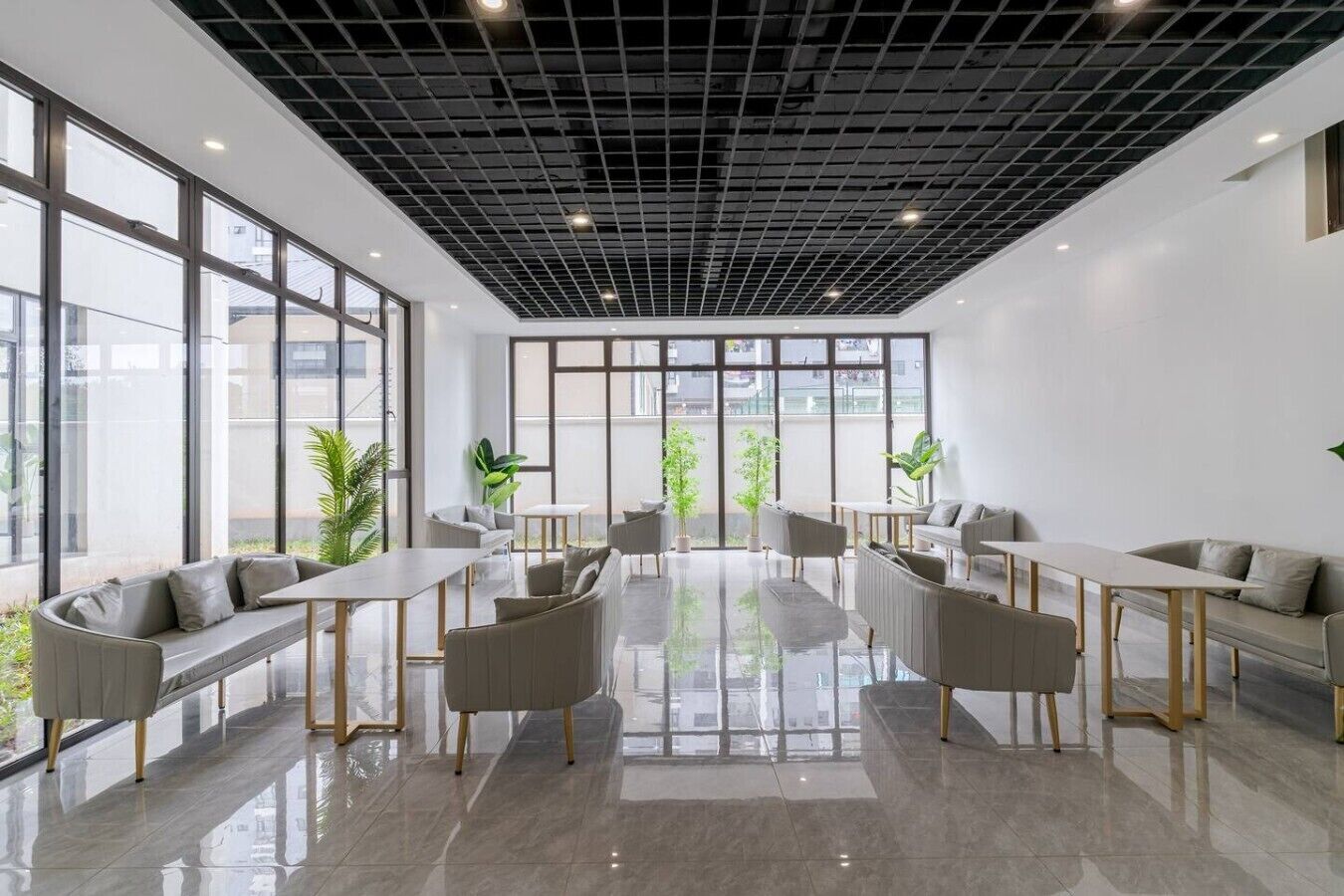 Un interior moderno con una zona de estar central, ventanas amplias y un techo con diseño de cuadrícula.