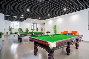 A pool hall with multiple tables, green felt tables, and orange seating. - Azure Luxe Residence (Nairobi)