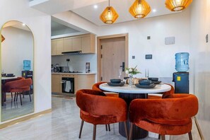 A modern dining area with a round table, red velvet chairs, and pendant lighting. - Azure Luxe Residence (Nairobi)