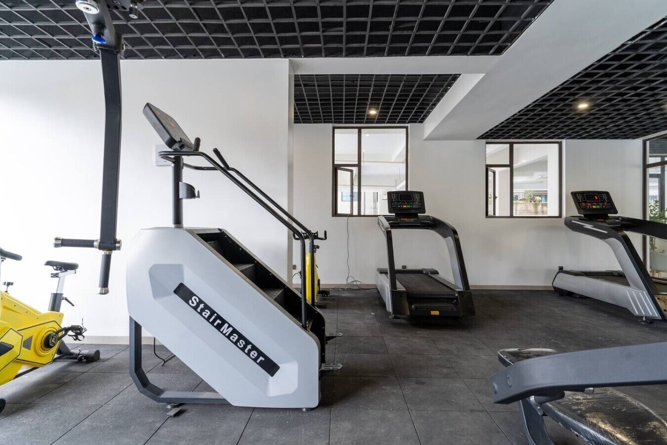 Een fitnessruimte met een stairmaster, loopbanden en een hometrainer.