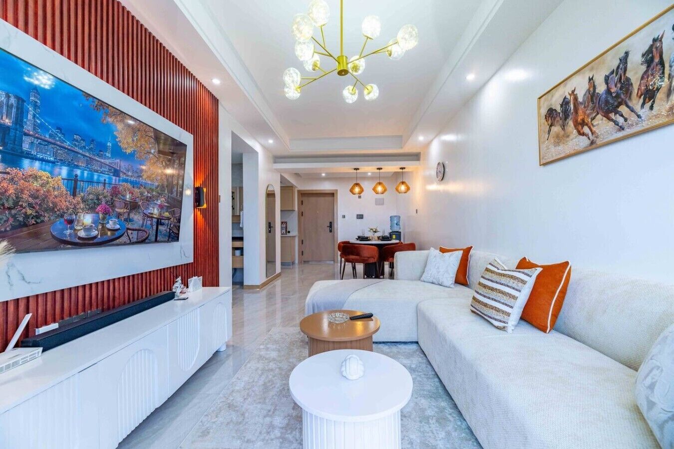A modern living room with a sofa, coffee table, and a dining area in the background.