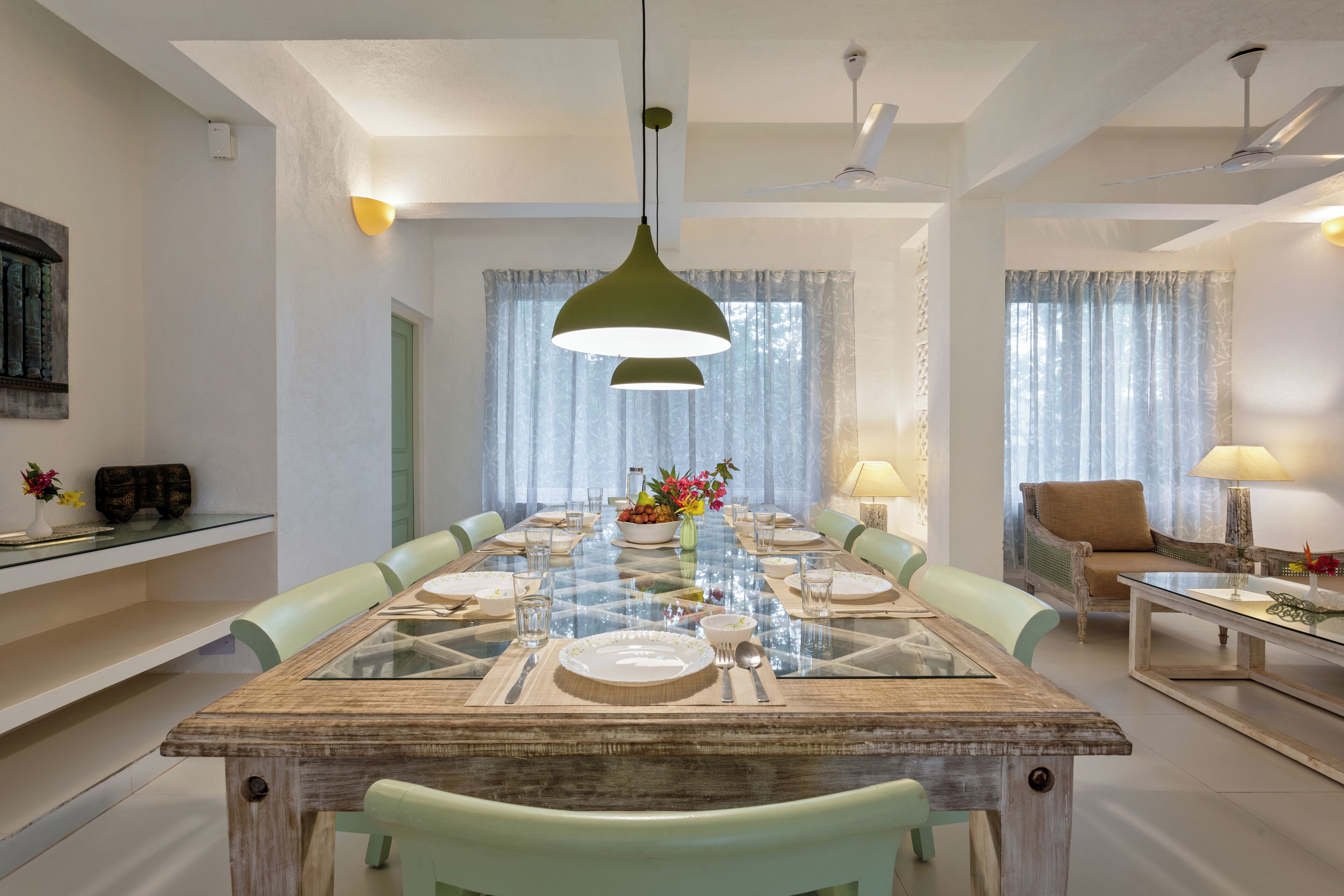 A dining area with a glass-top table, chairs, and a pendant light.